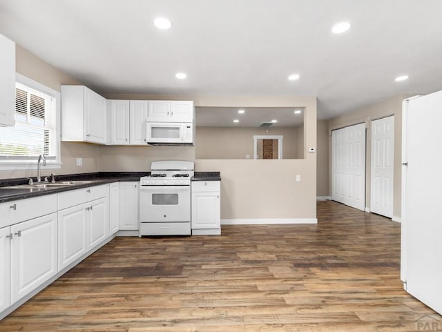 2619 7th Ave, Pueblo, CO 81003 - kitchen with white appliances, wood finished floors, white cabinets, dark countertops, and recessed lighting