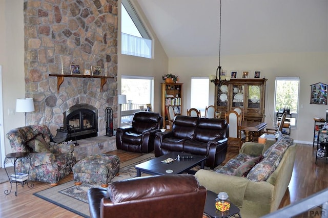 205 Hoofprint Ct, Walsenburg, CO 81089 - living area with wood finished floors, healthy amount of natural light, a stone fireplace, high vaulted ceiling, and a chandelier