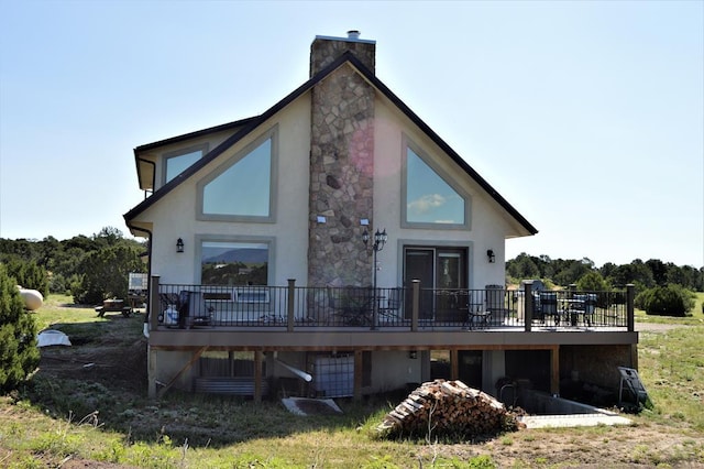205 Hoofprint Ct, Walsenburg, CO 81089 - rear view of property with stucco siding, a wooden deck, stone siding, and a chimney
