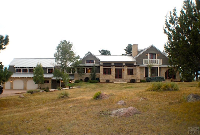 view of front facade featuring a chimney, concrete driveway, a garage, stone siding, and a front lawn