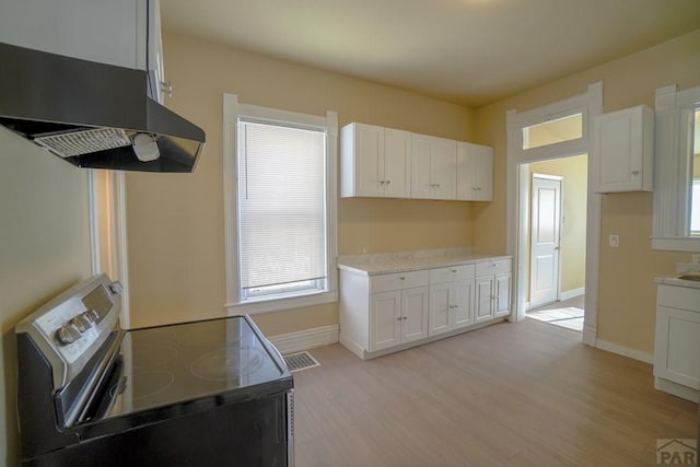 kitchen with electric stove, extractor fan, and white cabinets