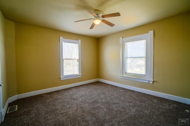 carpeted empty room with a ceiling fan, visible vents, and baseboards