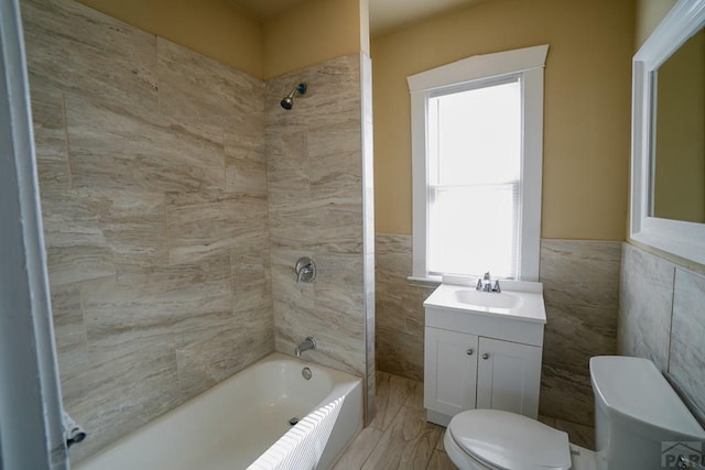 full bathroom with toilet, bathing tub / shower combination, vanity, and tile walls