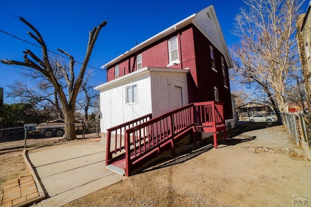 back of house with brick siding and fence