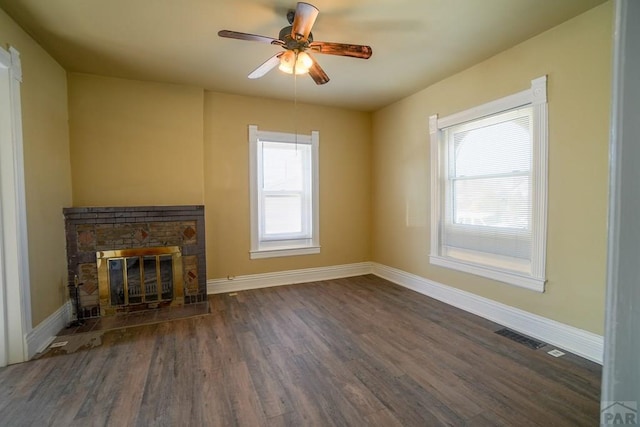 unfurnished living room with visible vents, baseboards, dark wood finished floors, ceiling fan, and a fireplace