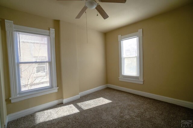 carpeted empty room with ceiling fan and baseboards