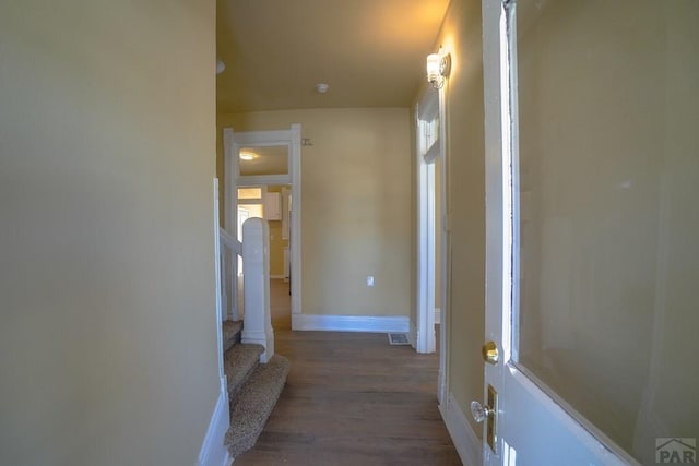 corridor featuring dark wood-style flooring, visible vents, baseboards, and stairs