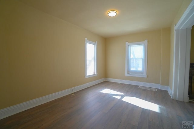 spare room featuring visible vents, baseboards, and wood finished floors