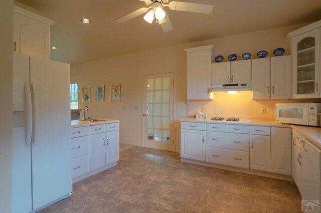 kitchen with under cabinet range hood, white appliances, white cabinetry, light countertops, and glass insert cabinets