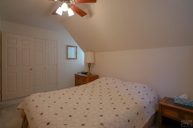 bedroom featuring lofted ceiling, ceiling fan, a closet, and carpet