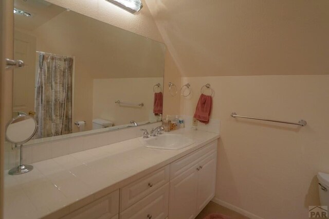 full bathroom with lofted ceiling, a shower with shower curtain, toilet, vanity, and baseboards