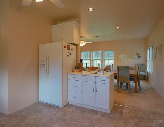 kitchen featuring light countertops, white cabinetry, a sink, ceiling fan, and white fridge with ice dispenser