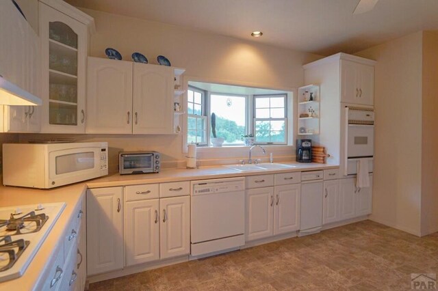 kitchen with light countertops, white appliances, a sink, and white cabinetry