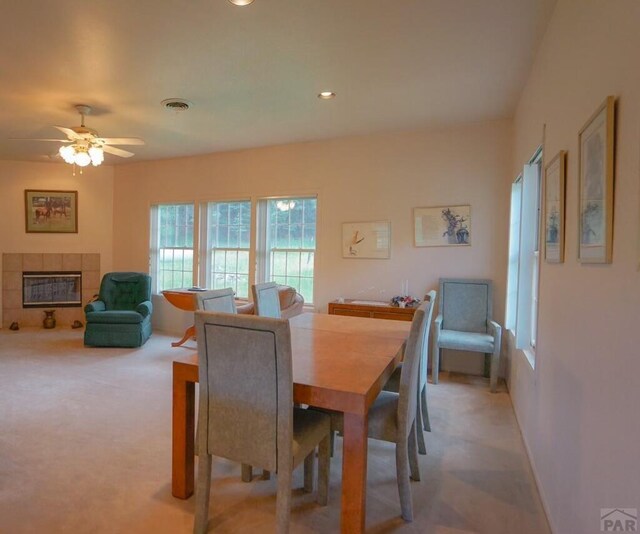 carpeted dining room with ceiling fan, visible vents, a tiled fireplace, and recessed lighting