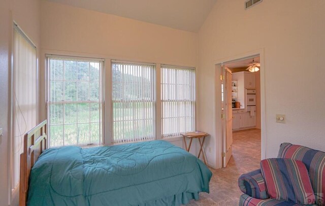 bedroom featuring lofted ceiling, multiple windows, light carpet, and visible vents