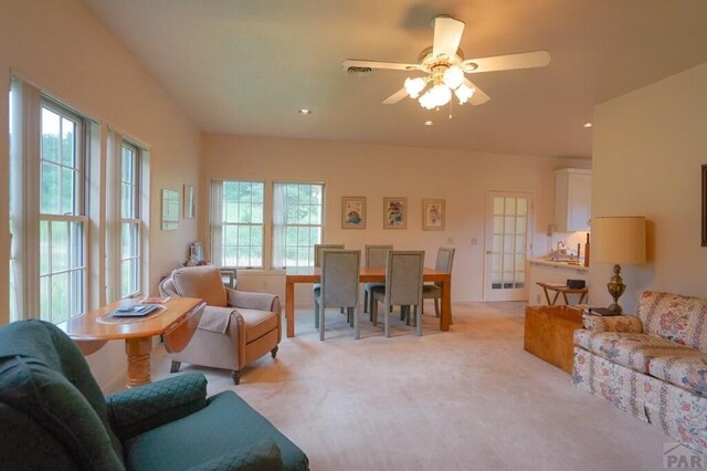 living area featuring light carpet and a ceiling fan