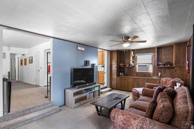 living area featuring wood walls, a ceiling fan, cooling unit, and light carpet