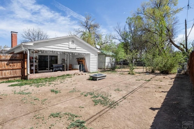 back of house featuring a fenced backyard, an outdoor fire pit, and a patio