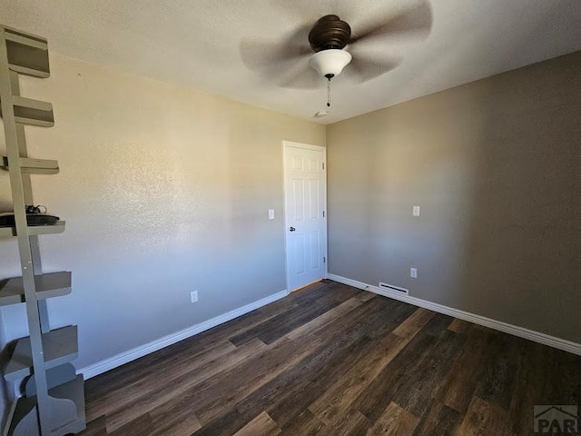 spare room with a ceiling fan, baseboards, and dark wood-style flooring