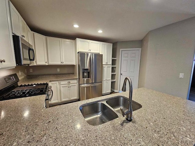 kitchen with light stone counters, recessed lighting, appliances with stainless steel finishes, white cabinets, and a sink