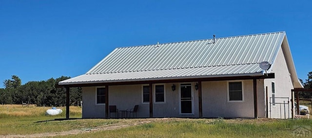 rear view of house featuring stucco siding and metal roof