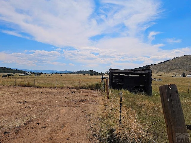 view of yard with a rural view, fence, and a mountain view