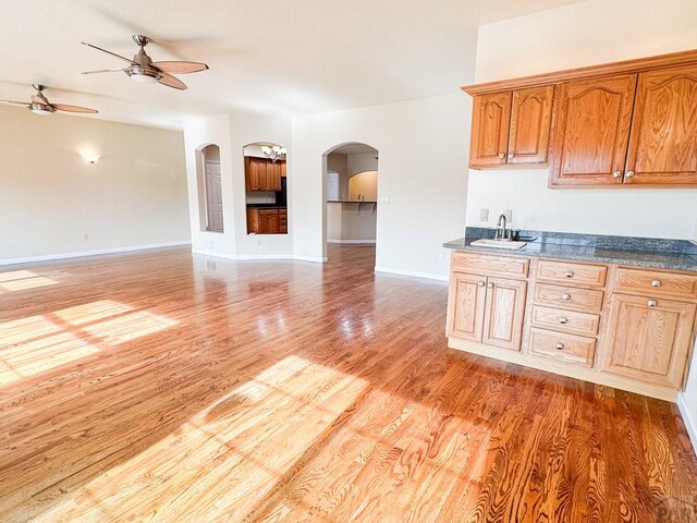 kitchen with light wood-type flooring, arched walkways, open floor plan, and a sink