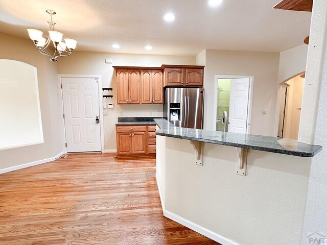 kitchen featuring dark countertops, brown cabinetry, and stainless steel refrigerator with ice dispenser