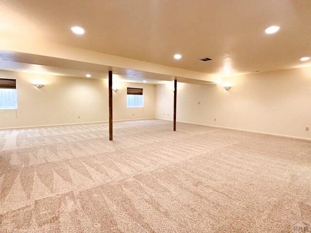 below grade area featuring recessed lighting, visible vents, and light colored carpet