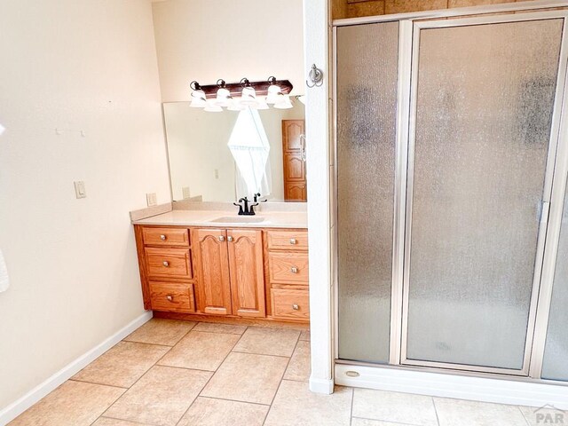 bathroom featuring a stall shower, tile patterned flooring, baseboards, and vanity