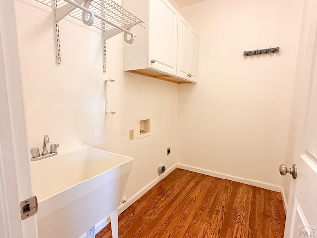 clothes washing area with washer hookup, cabinet space, a sink, wood finished floors, and baseboards