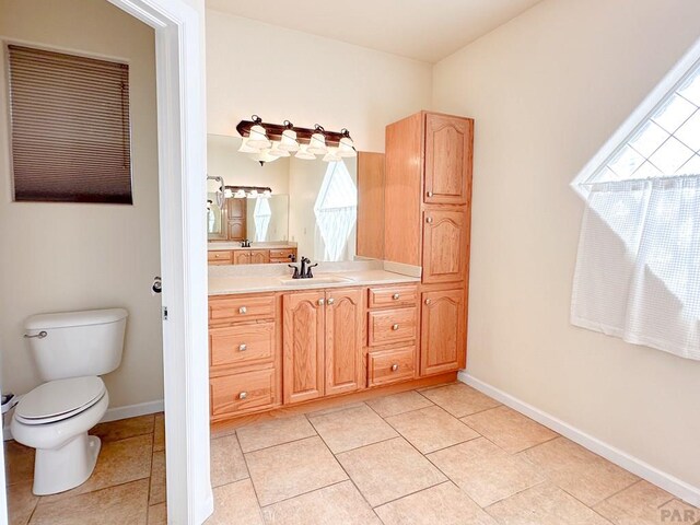 bathroom with toilet, tile patterned floors, baseboards, and vanity