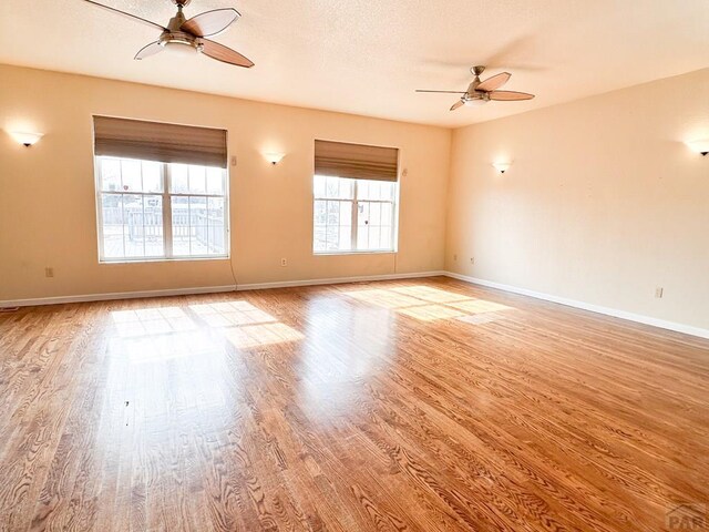 empty room with light wood-style floors, ceiling fan, and baseboards