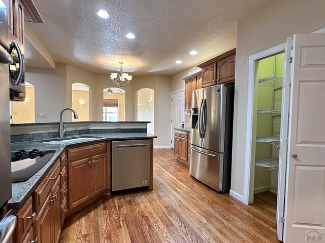 kitchen featuring a textured ceiling, stainless steel appliances, a sink, and wood finished floors