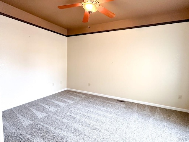 carpeted empty room featuring a ceiling fan, visible vents, and baseboards