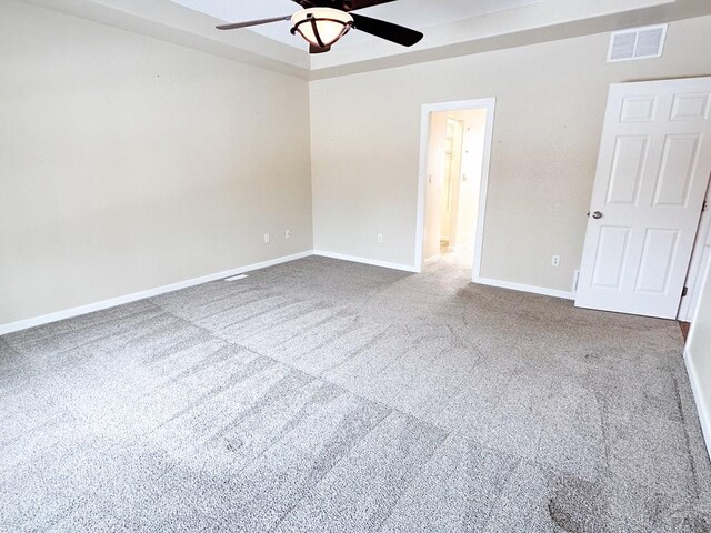 carpeted empty room featuring baseboards, visible vents, and ceiling fan