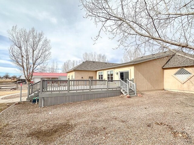 back of house featuring a deck and stucco siding