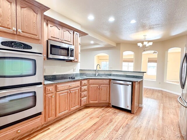 kitchen with a textured ceiling, recessed lighting, a sink, appliances with stainless steel finishes, and light wood finished floors