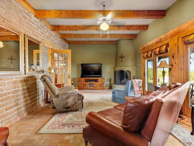 living area with ceiling fan, brick wall, and beam ceiling