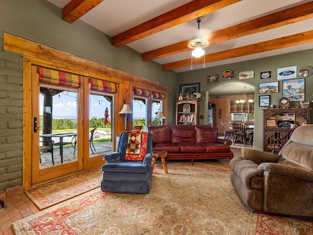 living room with brick wall, arched walkways, beam ceiling, and ceiling fan with notable chandelier