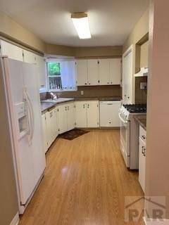417 Park Dr, Pueblo, CO 81005 - kitchen featuring white appliances, dark countertops, light wood-style floors, and white cabinetry