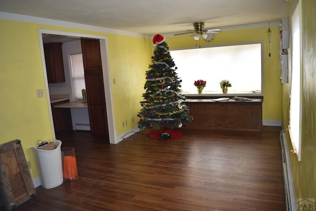 interior space featuring a baseboard heating unit, baseboards, ceiling fan, wood finished floors, and a baseboard radiator