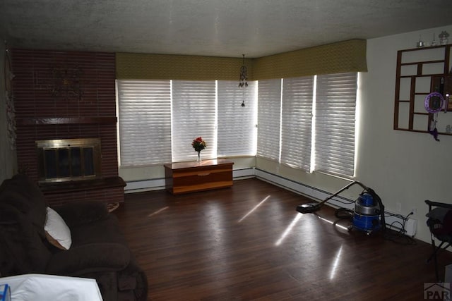 living room featuring a baseboard radiator, a fireplace, a textured ceiling, and wood finished floors