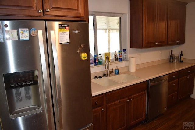 kitchen featuring a sink, stainless steel appliances, dark wood-style flooring, and light countertops