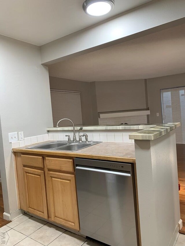 kitchen featuring dishwasher, light countertops, light tile patterned floors, and a sink