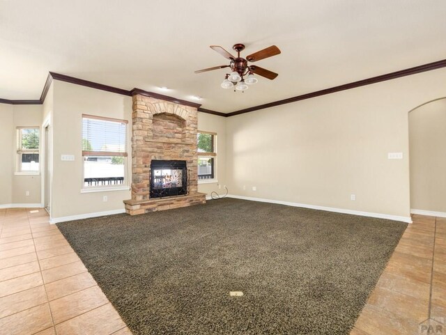 1705 Aquila Dr, Pueblo, CO 81008 - unfurnished living room with light tile patterned flooring, ceiling fan, healthy amount of natural light, a stone fireplace, and ornamental molding