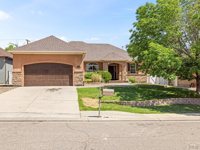 1705 Aquila Dr, Pueblo, CO 81008 - view of front of property featuring stone siding, an attached garage, a front lawn, and concrete driveway