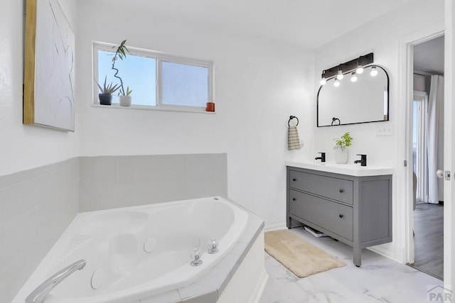 full bath with marble finish floor, a garden tub, and vanity