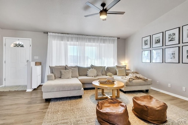 living area with vaulted ceiling, ceiling fan, baseboards, and wood finished floors