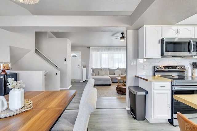 kitchen featuring stainless steel appliances, light wood-type flooring, decorative backsplash, and white cabinets